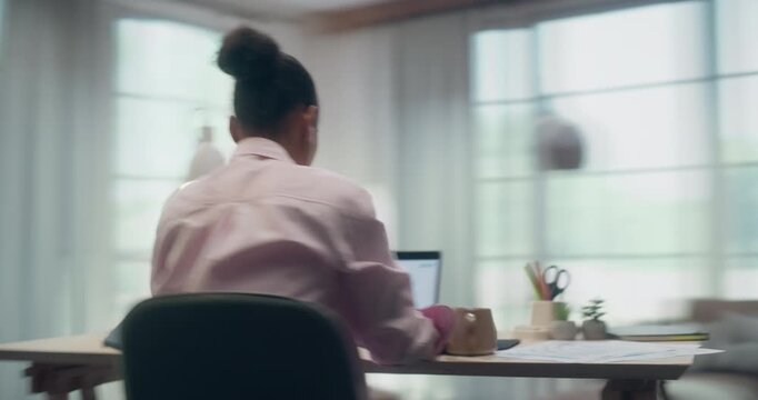 360 Degree Timelapse. Young Black Female Working Remotely on Laptop Computer at Home Desk, Browsing Internet, Reviewing Documents and Listening to Music With Earphones. Cinematic Arc Tracking Shot.