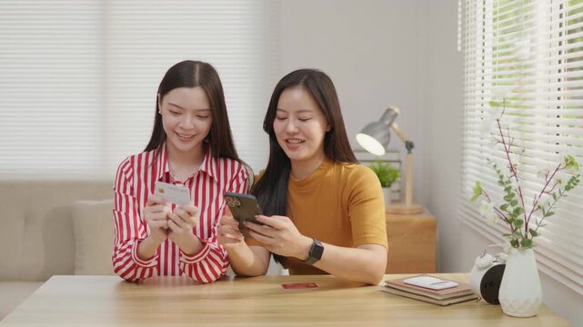 Two women using a credit card for online payment on a smartphone, ideal for e-commerce, mobile banking, digital transaction, online shopping and cashless payment concepts.