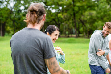 Fototapeta premium Smiling Asian woman laughing with men during outdoor group activity