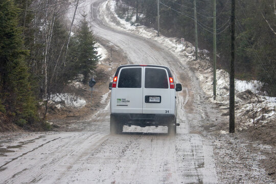 Canada, 13 April 2026 : Ecole Forestiere van drives on a muddy snowy unpaved road through a forest