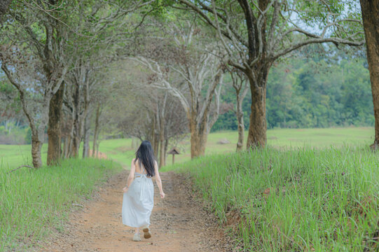 Young Woman in White Outfit Walking a Scenic Path in Khao Yai, Thailand