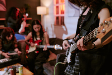 Fototapeta premium Teenage girls rehearsing with electric guitars and keyboard in home studio, collaborating on music production and creative teamwork. Useful for youth culture, music education, band promotion