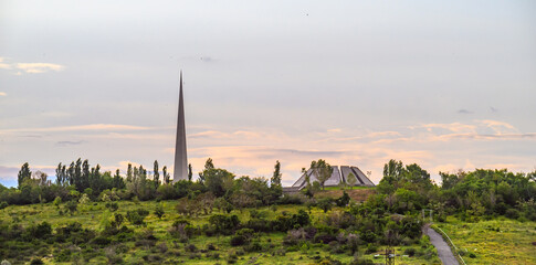 Fototapeta premium Armenian Genocide Memorial stands tall over grassy field with scattered trees