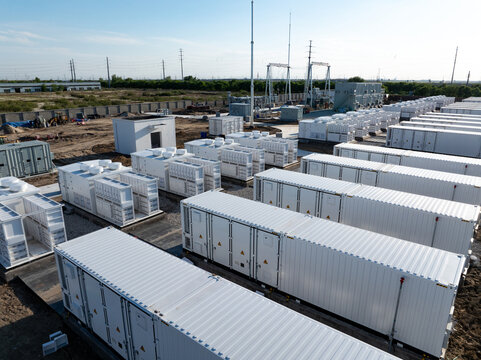 Large outdoor array of energy storage battery containers at a power facility site