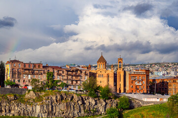 Obraz premium City skyline with church towers and terracotta roofs under rainbow