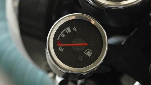  Close-up of a round motorcycle fuel gauge with a red needle pointing to empty.
