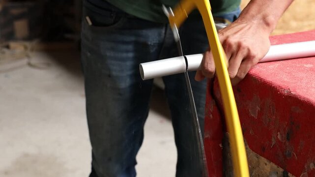 Craftsman using a hacksaw to cut a metal pipe for a traditional handmade project