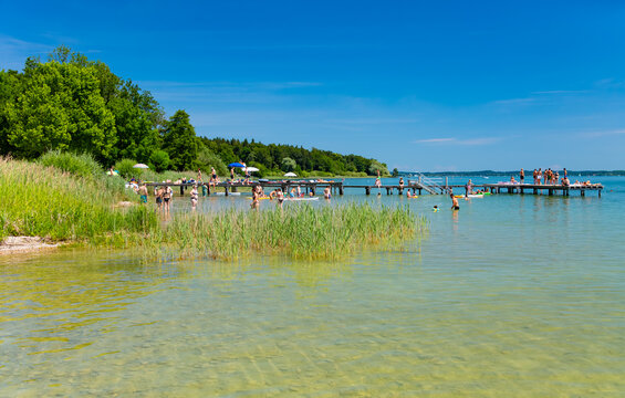 Summer fun at a swimming pier on Lake Chiemsee in Bavaria (Germany). Many people are enjoying sunbathing by the crystal-clear waters of the lake and cooling off with water sports.