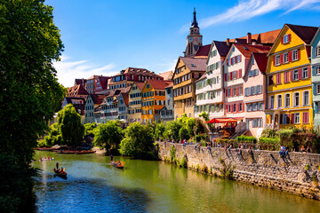 Obraz premium Tuebingen popular university town in southern Germany. “Neckarfront“ with colorful facades, church (Stiftskirche) and poled boats (Stocherkahn) on the River Neckar on a sunny summer day.