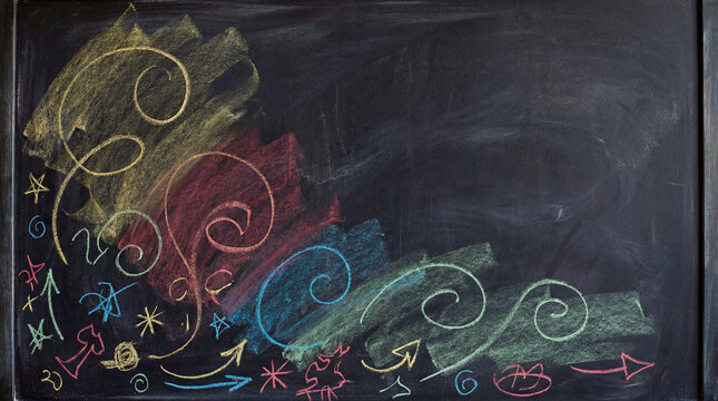 Colorful chalk doodles and swirls drawn on a dark blackboard with copy space for school