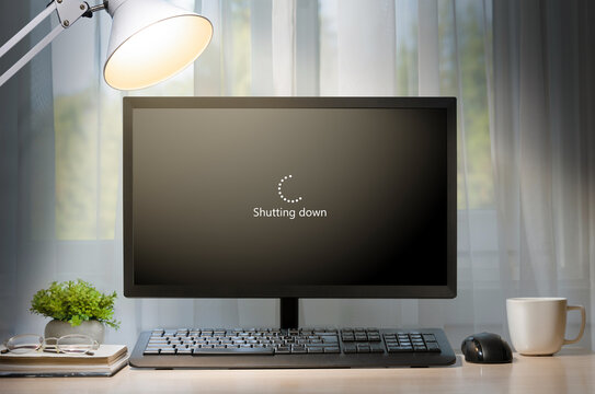 A workstation with a computer with the word "Shutting down" written on the screen. The concept of ending the workday.