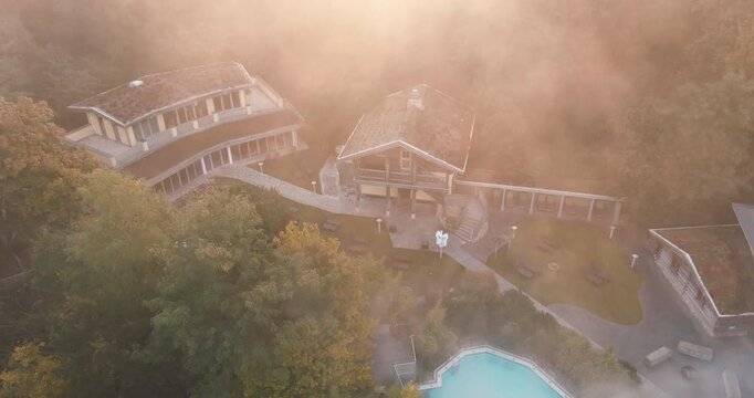 Aerial view through morning mist of a luxury hotel resort property hidden in a dense green forest
