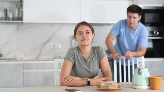 Guy argues with girl in kitchen, expressing his dissatisfaction and indignation.