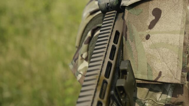 Camouflaged soldier in the middle of wilderness on a recon mission. Carrying an AR-15 carbine rifle with a red collimator and a magnifier