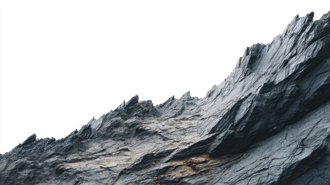 Jagged mountain cliff against clear white sky. Rough dark shale rock texture for geological background. Natural stone formation, wilderness landscape, rugged terrain, geology concept.