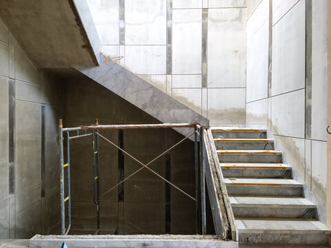 Precast concrete staircase structure with gray marble cladding being installed using steel scaffolding at a building project.