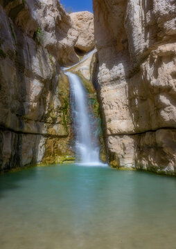 Hidden Falls in Ein Gedi Nature Reserve cascade into a tranquil oasis surrounded by dramatic desert cliffs near the Dead Sea. 