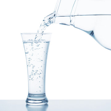 fresh water pouring from decanter into transparent glass isolated on white background