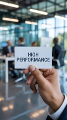 Obraz premium Person holds a white performance message card in a bright contemporary office setting