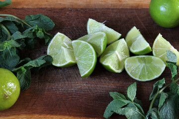 Lime wedges and fresh green mint on a wooden board. Juicy, ripe lime and aromatic mint leaves are excellent ingredients for summer lemonade. Food. Bright summer background. Citrus. Vitamins. Lime. © Татьяна Сычёва