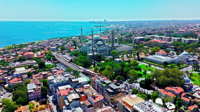 Aerial view of Istanbul, Turkey near Hagia Sophia Grand Mosque. The mosque area sits beside green parks, rooftops and the blue sea in the distance.