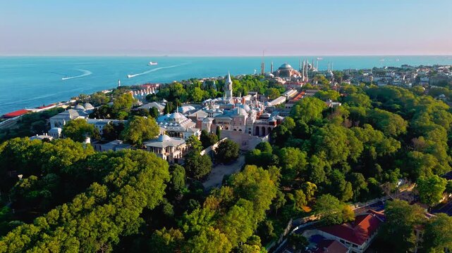 Drone view near Topkapi Palace Museum in Istanbul, Turkey. Dense trees, historic architecture and the blue waters in the distance give this scene a calm and scenic atmosphere.