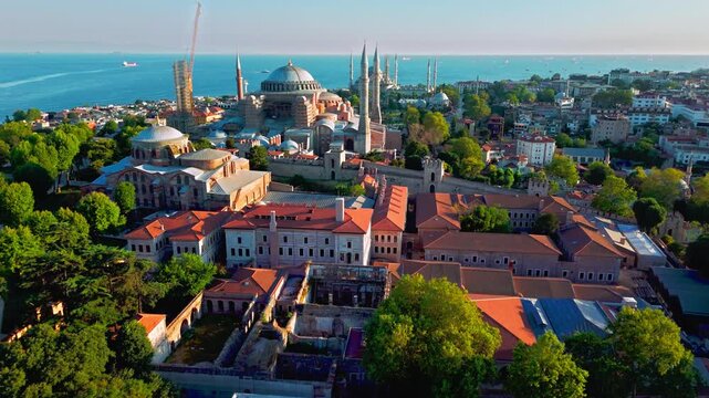 Aerial view of Hagia Sophia Grand Mosque in Istanbul, Turkey. The historic landmark stands with large domes and tall minarets near the Blue Mosque, Sultanahmet Square and the blue Bosphorus.