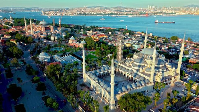 Drone view of the Blue Mosque and Sultanahmet district in Istanbul, Turkey. Sultanahmet Camii rises above historic rooftops, tree-lined streets and the blue sea.