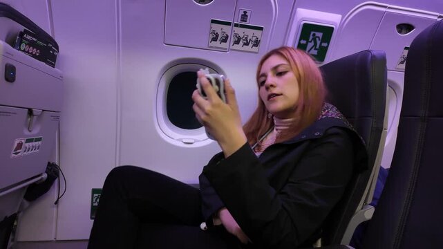 Woman Using Phone on Airplane in Casual Attire