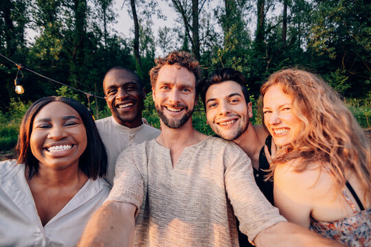 Diverse friends taking a selfie outdoors during sunset party
