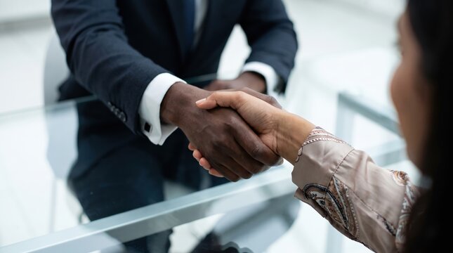 Close-Up of Diverse Professionals Handshake Over Glass Conference Table, Focused on Inclusive Hiring, Workplace Diversity, and Corporate Partnership Concept with Black and South Asian Individuals
