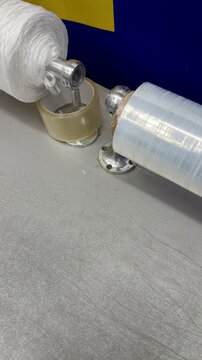 Transparent film white rope on counter showcasing closeup of dispenser with clear stretch film and dense white twine spool ready