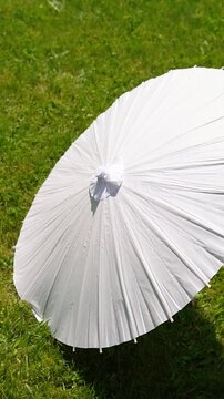 Stylish white vintage umbrellas provide shade from the hot, bright sun on a sunny summer day. Wedding ceremony for the bride and groom.