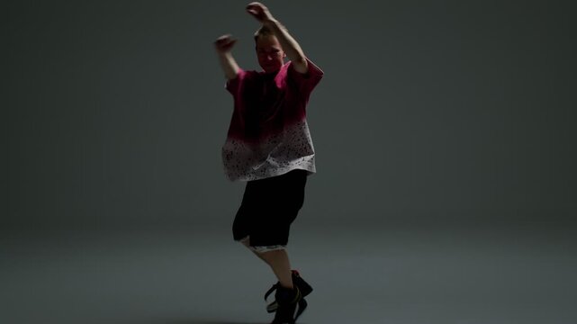 Hip hop dancer jumping with raised arms in studio