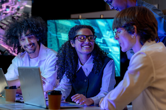 Low-light scene where a Latina software engineer leans toward the monitor working in a modern technology office bathed in blue light, a portrait of inclusion and collaboration (frame 306)
