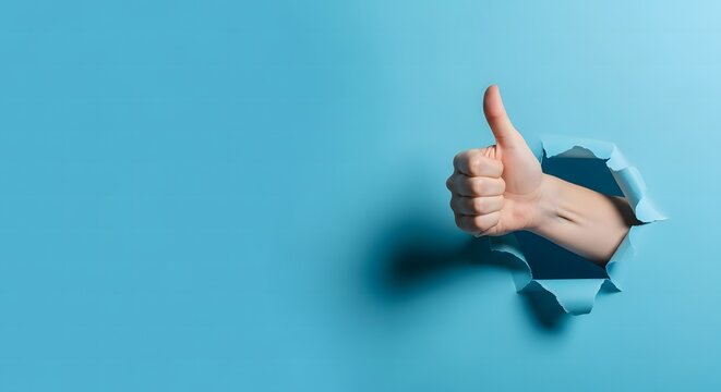 Hand giving thumbs up through torn blue paper