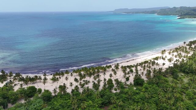 4K Aerial horizontal pan left view of Playa Rincon in Las Galeras, drone panning showing Ca&ntilde;o Frio river mouth, white sand beach with palm trees, and turquoise ocean, Dominican Republic.