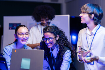Obraz na płótnie Canvas Wide shot of a diverse, multiethnic software team smile and cheer at their desks in a modern technology office bathed in blue light, capturing collaboration on an inclusive (frame 1035)