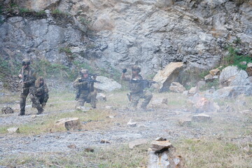 Fototapeta premium A group of soldiers in military uniforms carrying BB guns were randomly attacked and taken down during a military exercise while playing a game. 