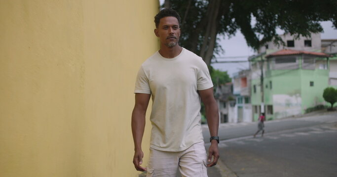 Hispanic Afro-Latin man walking forward, playfully scolding someone off-camera, animated expression, friendly neighborhood interaction, casual urban setting