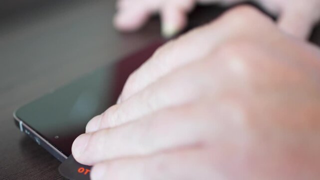 Man removing small dust from under smartphone screen protector with sticky tape close up.