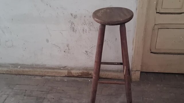 Rustic wooden stool standing in empty room motion video footage