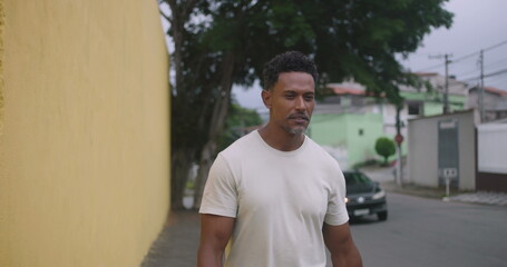 Fototapeta premium Hispanic Afro-Latin man walking forward, playfully scolding someone off-camera, animated expression, friendly neighborhood interaction, casual urban setting