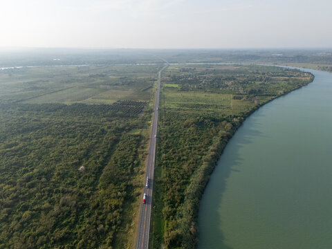 Elevated view showing the autopista tuxpan tampico highway running alongside the pantepec river, with trucks moving through the lush green landscape of veracruz, mexico