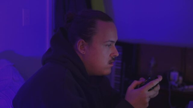 Young Man Gamer Playing on a Games Console in Blue Neon Bedroom