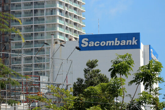 NHA TRANG, VIETNAM - JANUARY 26, 2026: A wide-angle street view featuring a large Sacombank sign on a building alongside a high-rise hotel tower under a blue sky