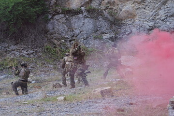 Fototapeta premium multinational group of male soldiers in infantry uniforms, carrying paintball guns and ready for combat, with pink smoke grenades and practicing military drills, with pink smoke signals 