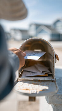 A person checking the mailbox on a sunny day with a rural backdrop.