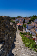 Fototapeta premium Óbidos is one of Portugal's best-preserved medieval towns, famous for its hilltop castle, whitewashed houses with blue and yellow trim, and walkable cobblestone streets surrounded by fortified walls.