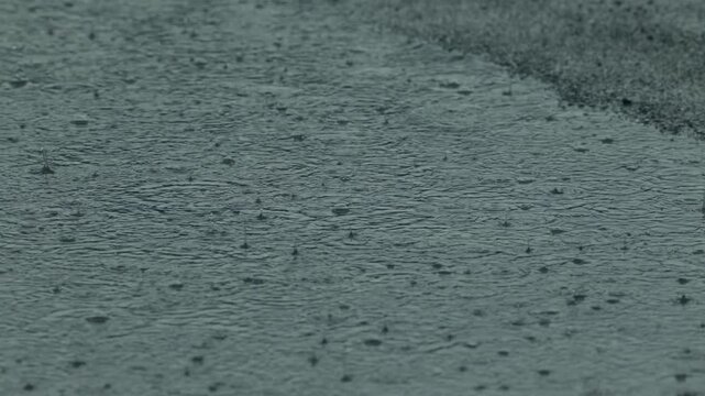 intensa pioggia e gocce d'acqua che cadono su un terreno urbano e creano pozzanghere di grandi dimensioni durante un temporale, video in tempo reale